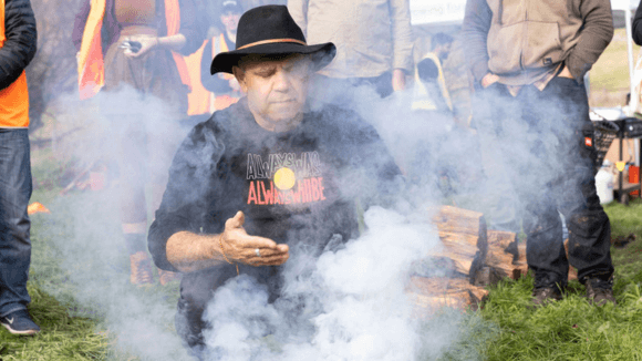 Photo of indigenous man performing a welcome to country, smoking ceremony. 